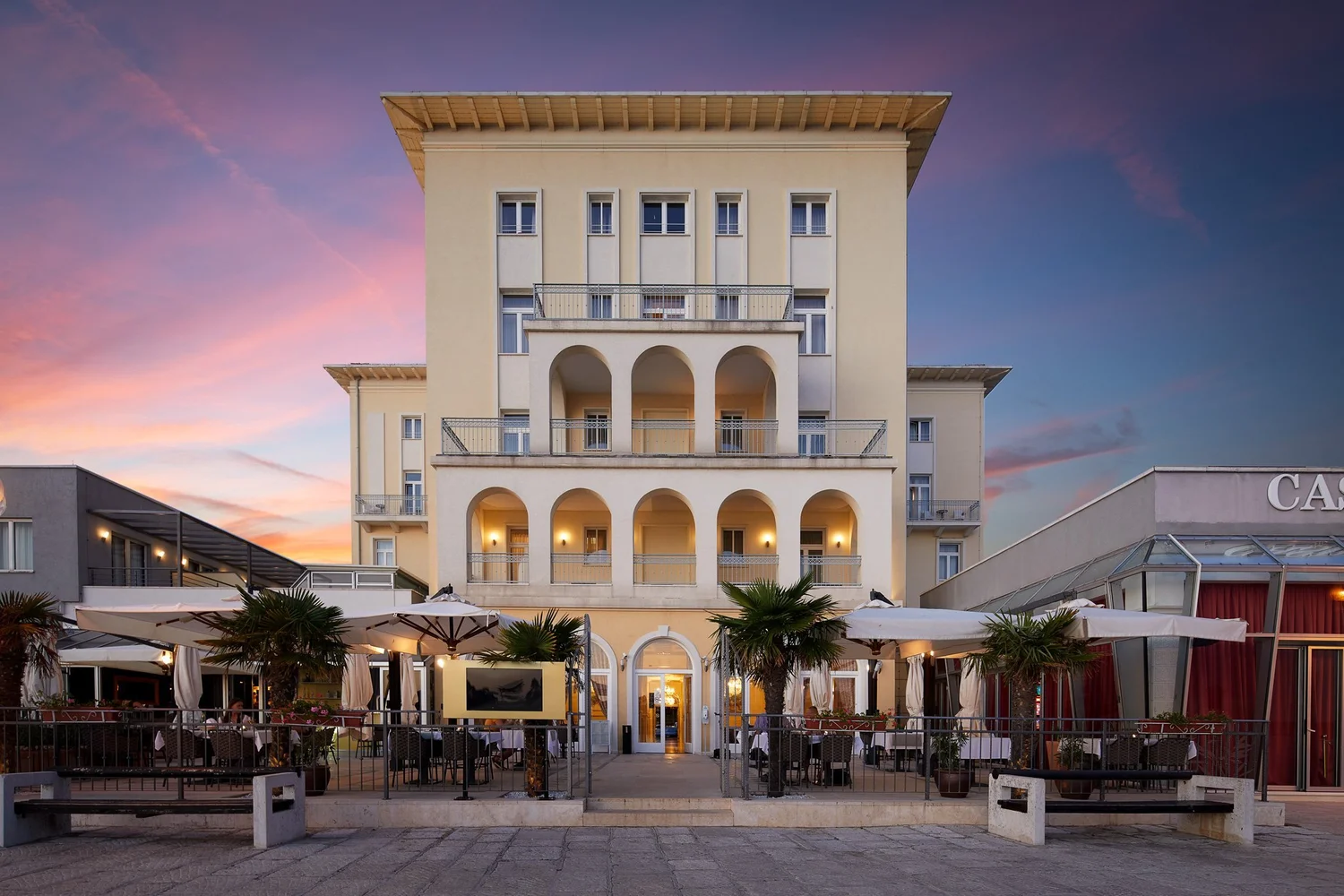 Fachada del BO Hotel Palazzo en Poreč al atardecer, junto al paseo marítimo.