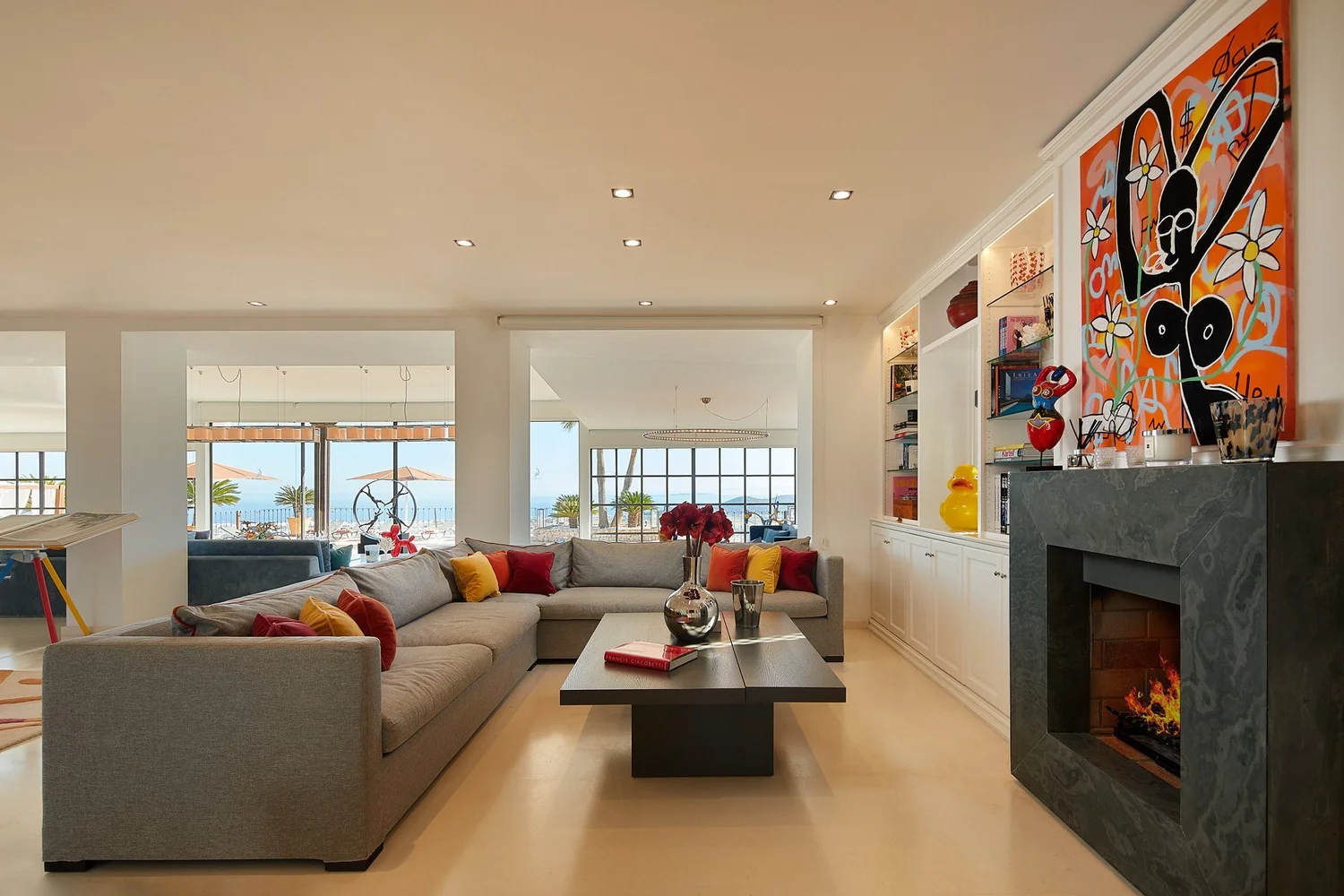 Sala de estar con chimenea, obras de arte y sofás en tonos grises.