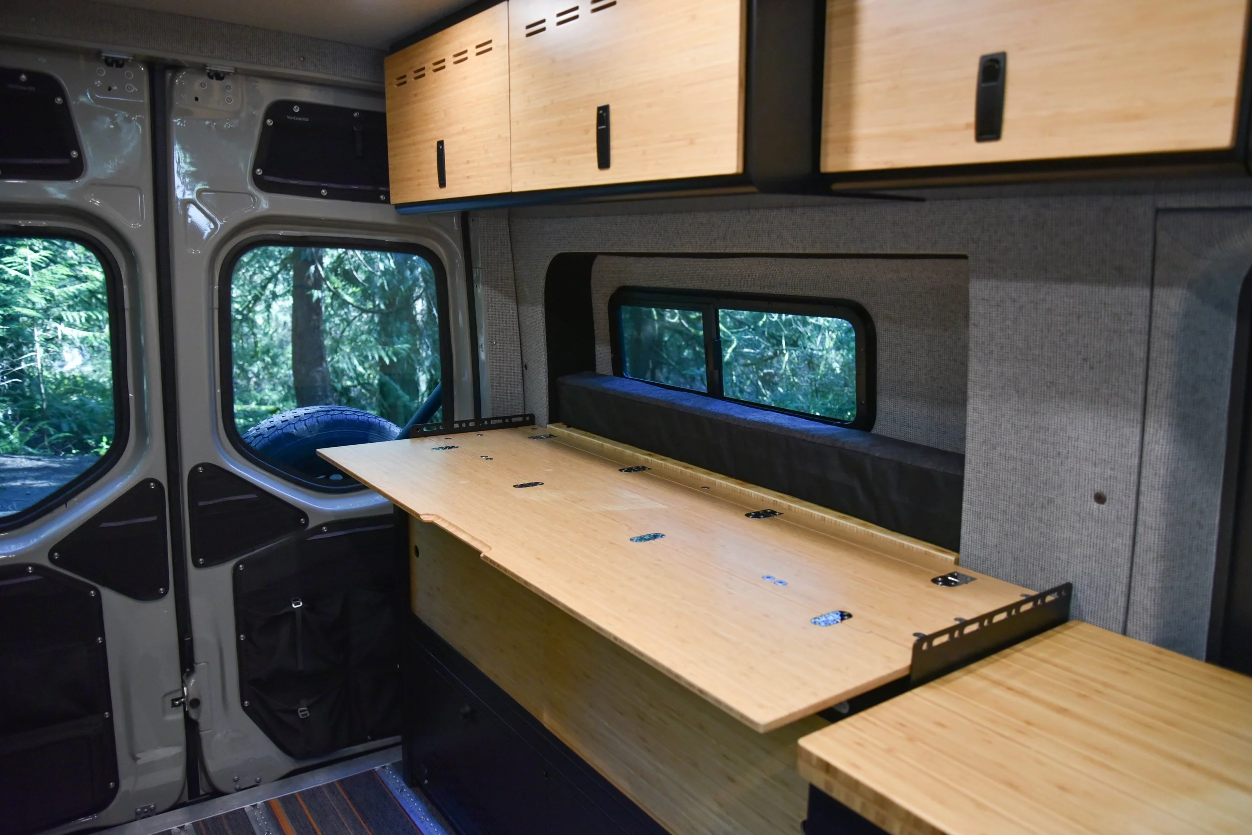 Premium camper van interior with wooden table and overhead cabinets