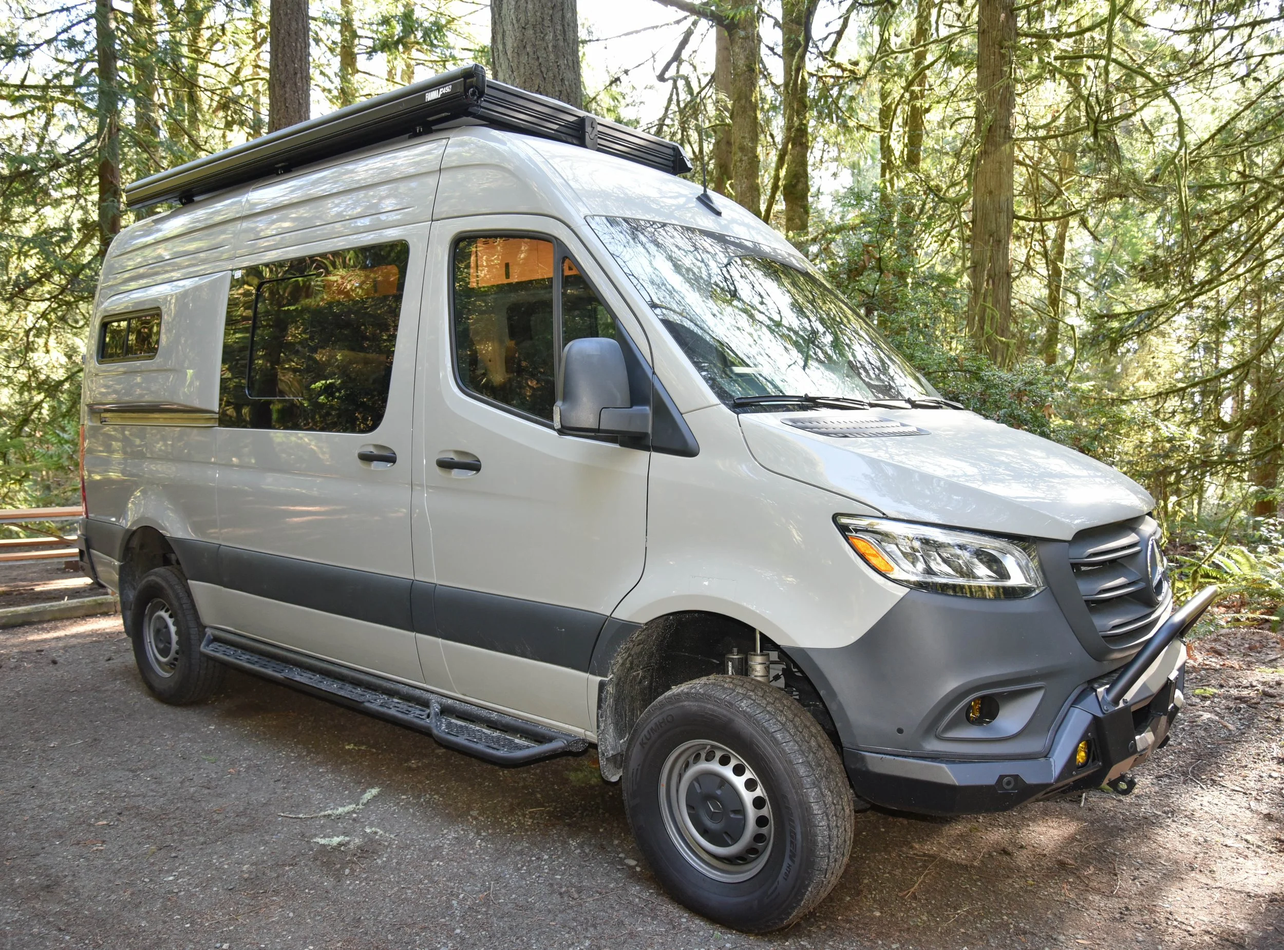 Camper van with pop-top roof at a forest campsite