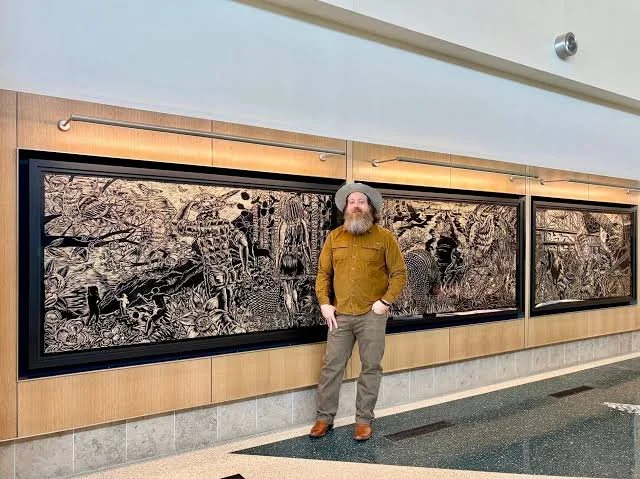 Neal Harrington standing in front of his woodcut triptych Arkansas As Home at the Little Rock airport