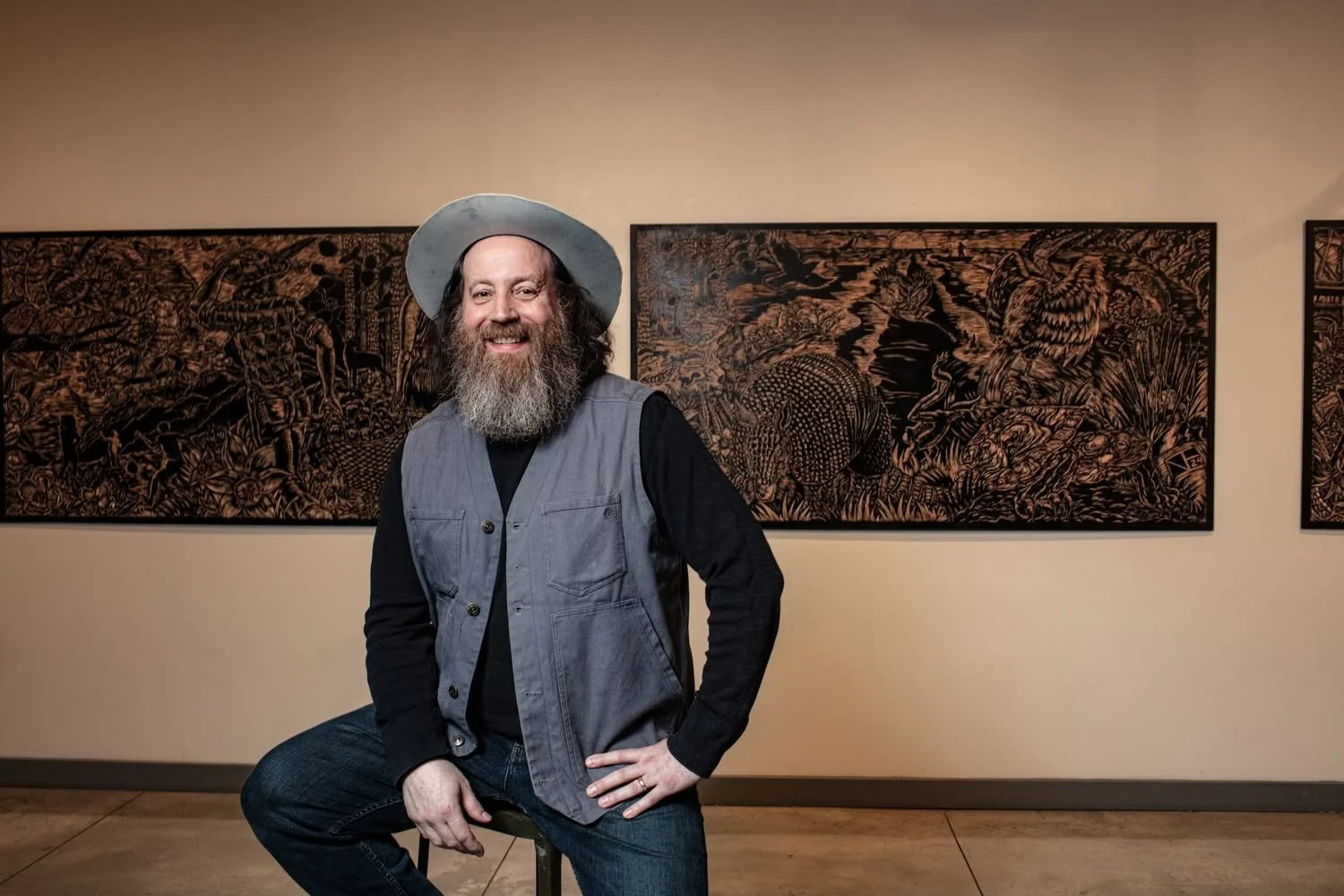 Neal Harrington seated in front of his large woodcut panels