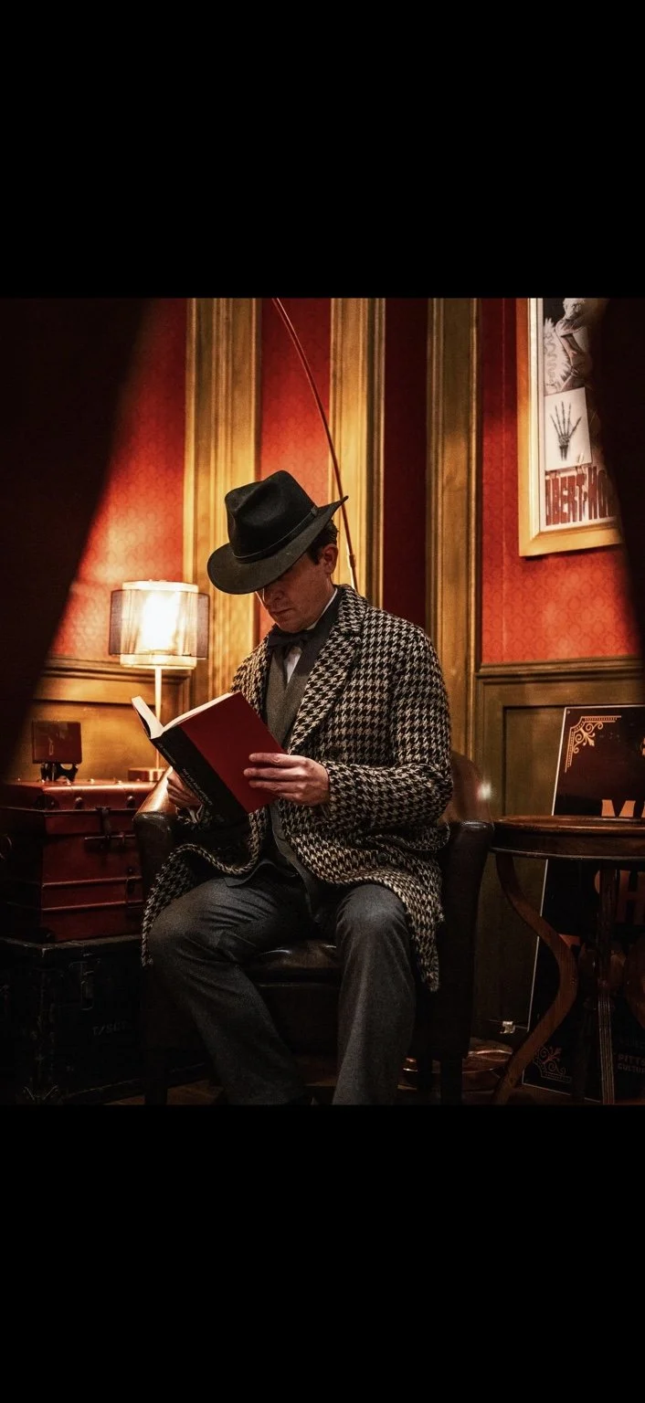 Lee Terbosic as Harry Houdini reading a book in his hat and houndstooth coat