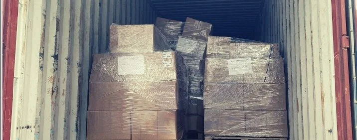 Shrink-wrapped pallets of repair units arriving in a shipping container