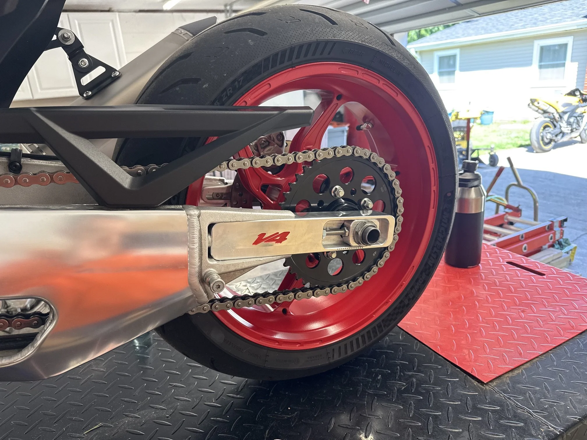 Aprilia V4 swingarm extension installed — close-up of CNC machined aluminum plates on swingarm