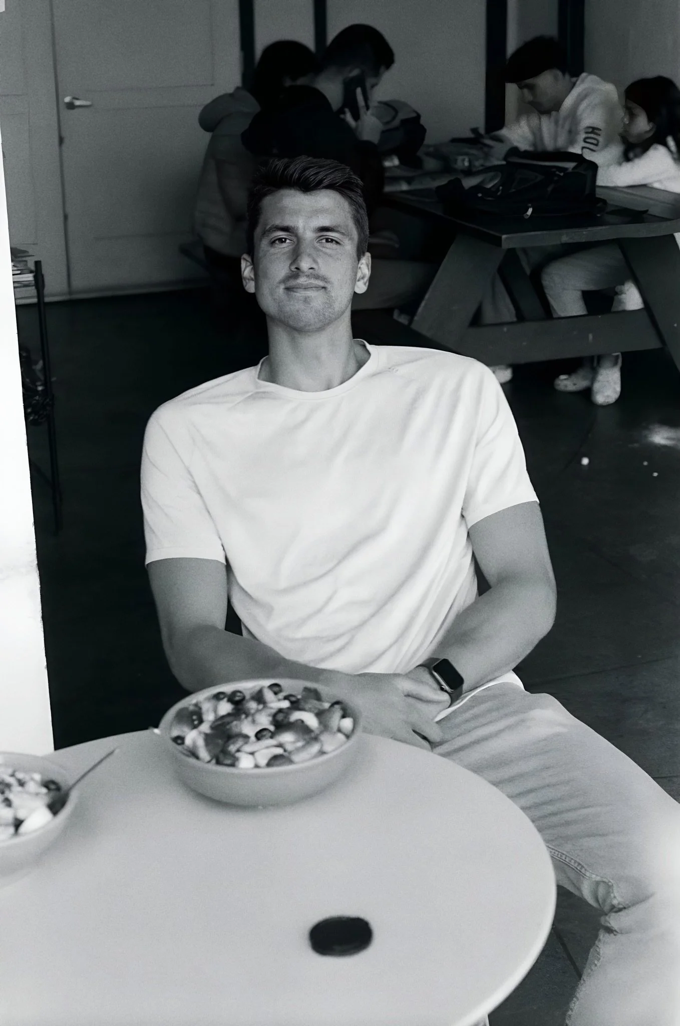 Bryce Ridenour seated at a café in a white T-shirt