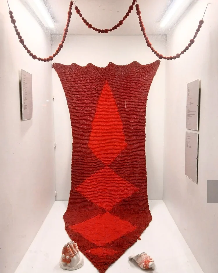 Alt Text: An image of the Akin Vitrine Gallery from the street, showing Charlotte Van Ryn’s exhibition All of the Glory, None of the Spending. Hung on the white walls of the vitrine gallery are poems on white paper in glass frames. 