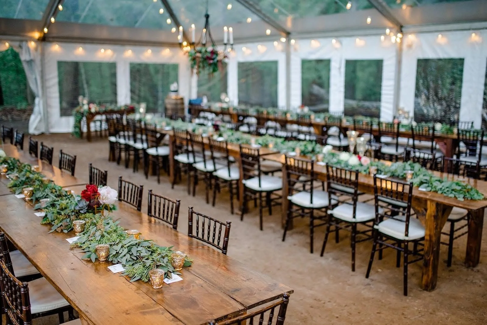 Farmhouse tables set up under a tent at a wedding reception