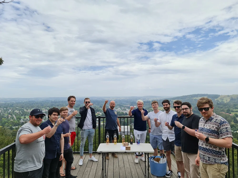 Southern Highlands wine and spirit tasting tour, guests toasting at a Highlands lookout A group of twelve guests raising spirit glasses around a tasting table at a lookout over the Southern Highlands.