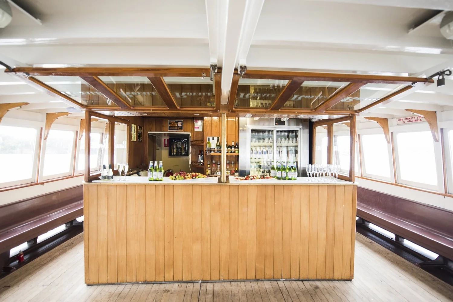 The timber bar set with drinks and platters on a Rosman heritage ferry, ready for a work function