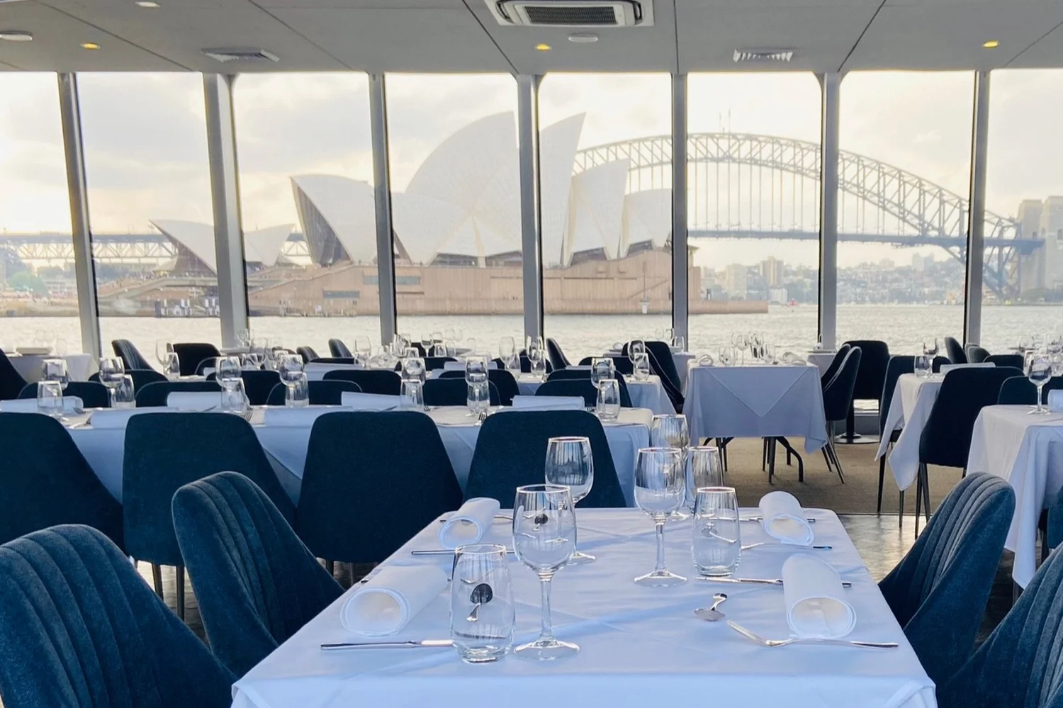 Clearview main deck set for a seated event, with floor-to-ceiling glass looking out to the Opera House and Harbour Bridge