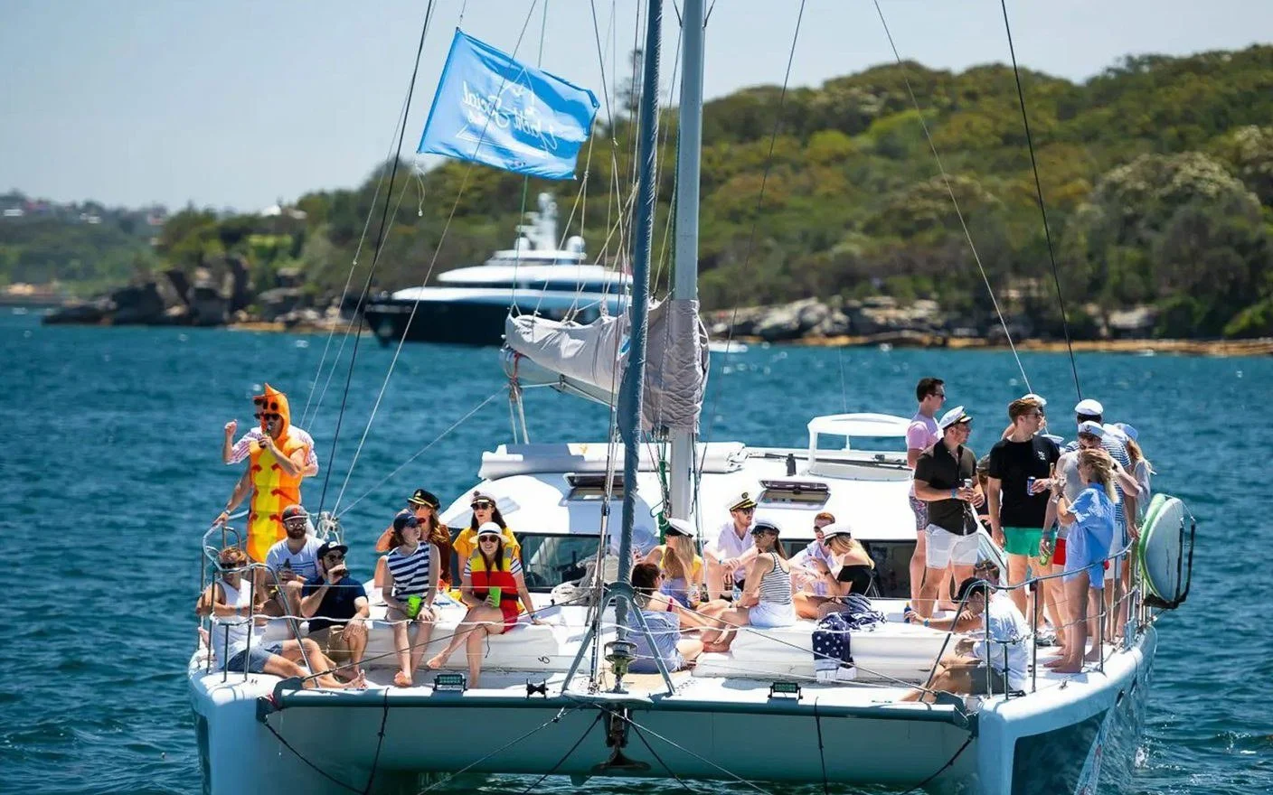 A party group in costume on the bow of the Barefoot sailing catamaran on Sydney Harbour