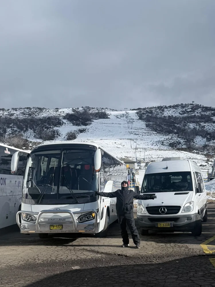 Group gathered in falling snow at the resort on a coach trip to the snow