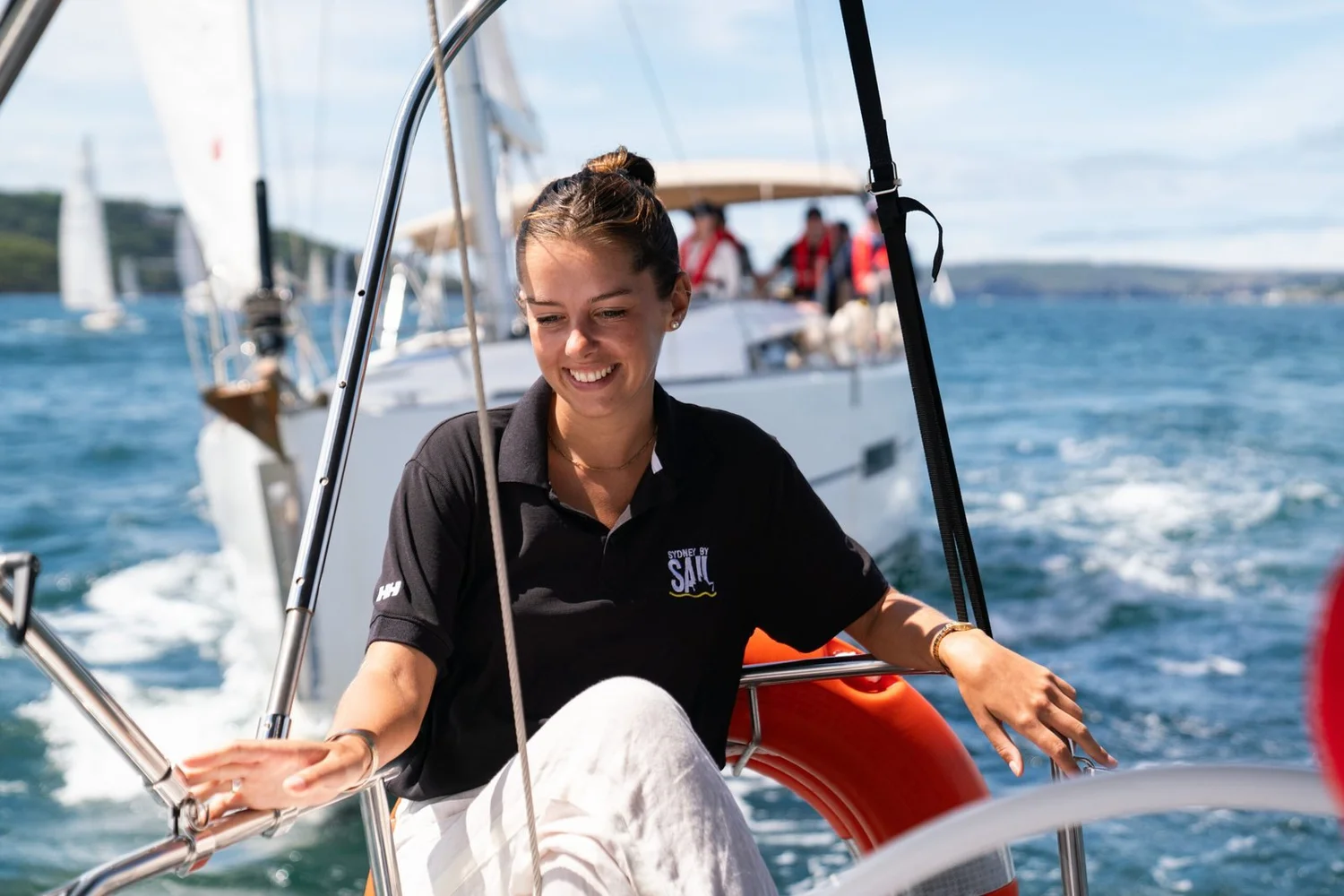 A See Sydney By Sail crew member at the helm during a team building regatta on Sydney Harbour
