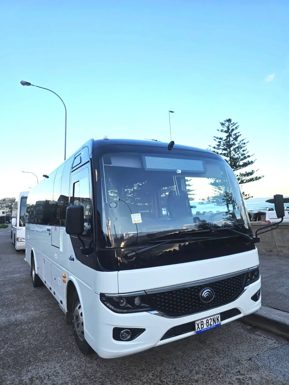 Urban Legends 27-seat coach parked outdoors for a Wollongong charter, white body with silver bull bar