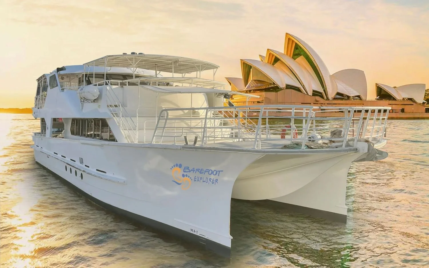 Barefoot Spirit, a 20m power catamaran, on Sydney Harbour at golden hour in front of the Sydney Opera House
