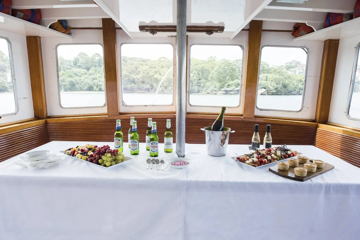 Platters, champagne and drinks set out on a white-clothed table in the timber cabin of Regal II