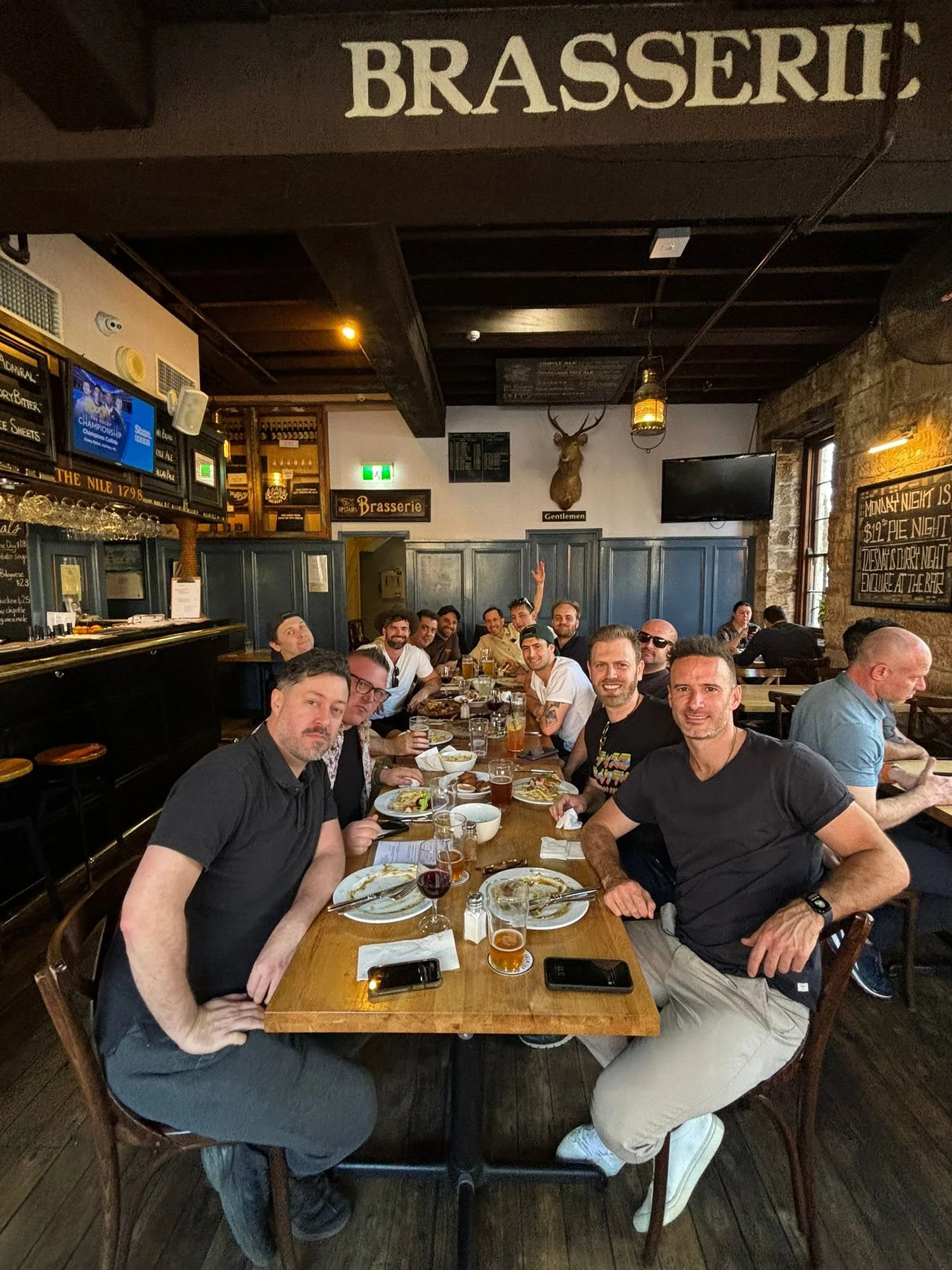 A group seated together for dinner under a brasserie sign in the Hunter Valley during a two night weekend brewery package.
