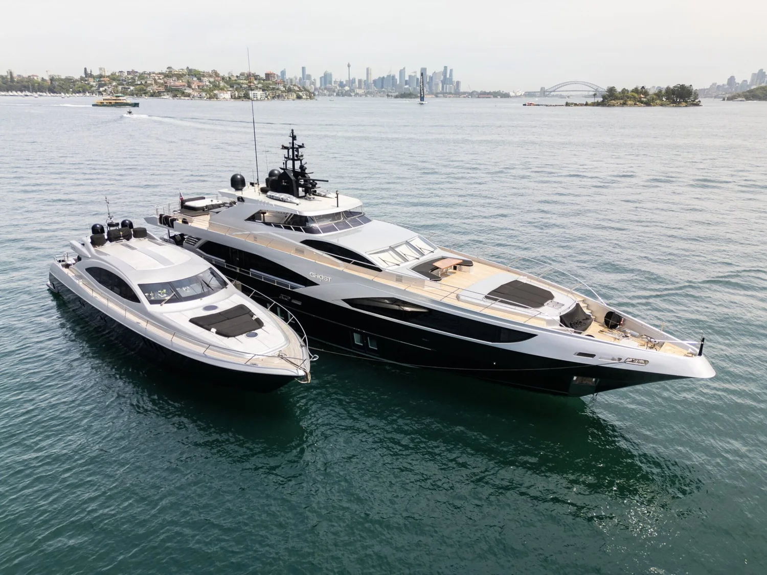 Two Ghost Charters superyachts at anchor on Sydney Harbour with the city skyline behind