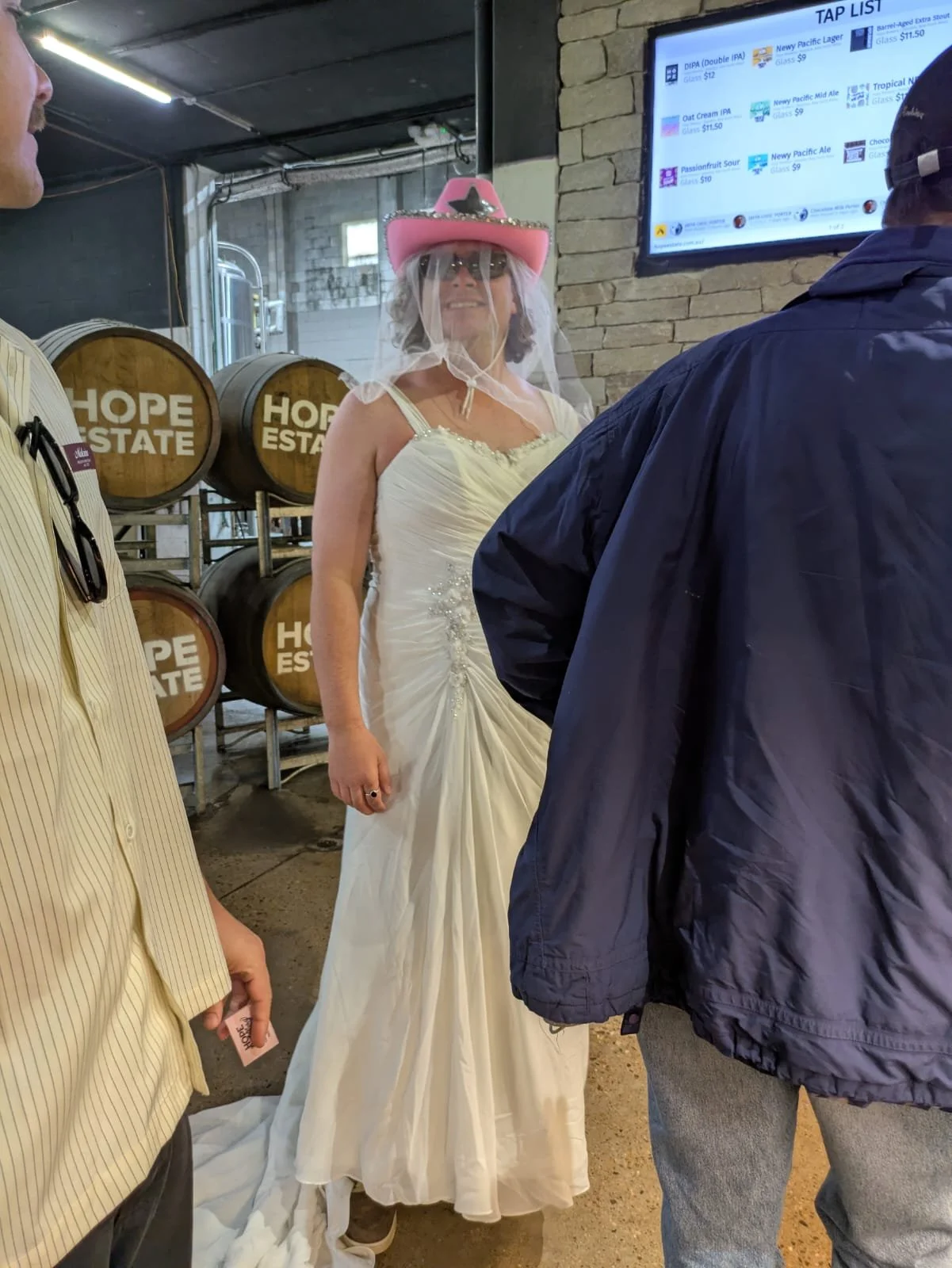 Buck in a wedding dress and pink hat beside Hope Estate barrels inside the brewery, Hunter Valley bucks party