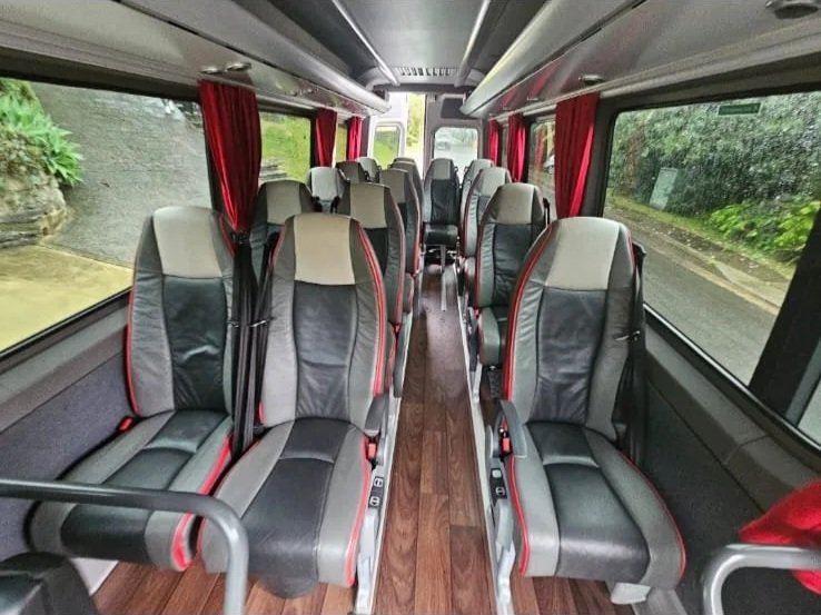 Interior of Urban Legends 14-seat Mercedes Sprinter minibus with red leather seats and curtains, Wollongong