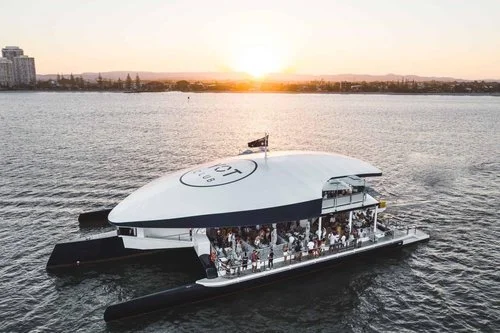 Catamaran on the water at sunset with a group aboard, Brisbane region