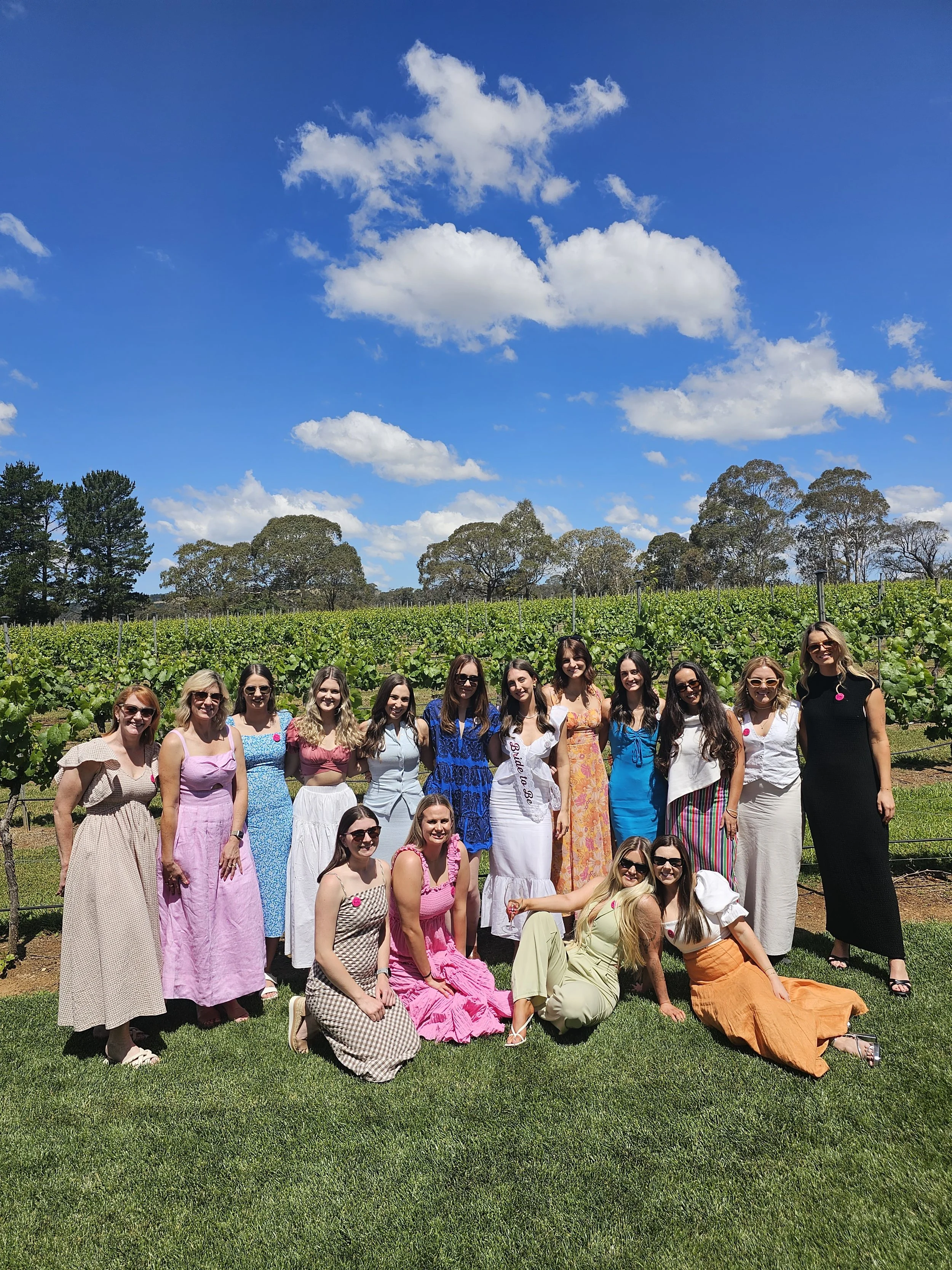 A hens group on a Southern Highlands wine tour standing in front of the vines on a clear day