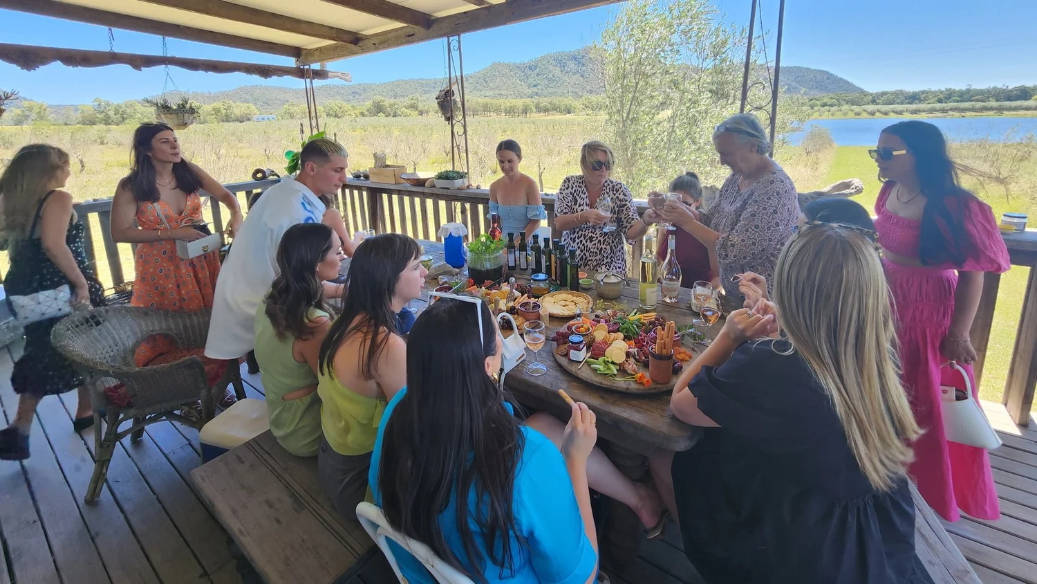 Around fourteen guests gathered around a grazing table on a winery deck overlooking a dam and the Brokenback Range on a Hunter Valley wine tour.