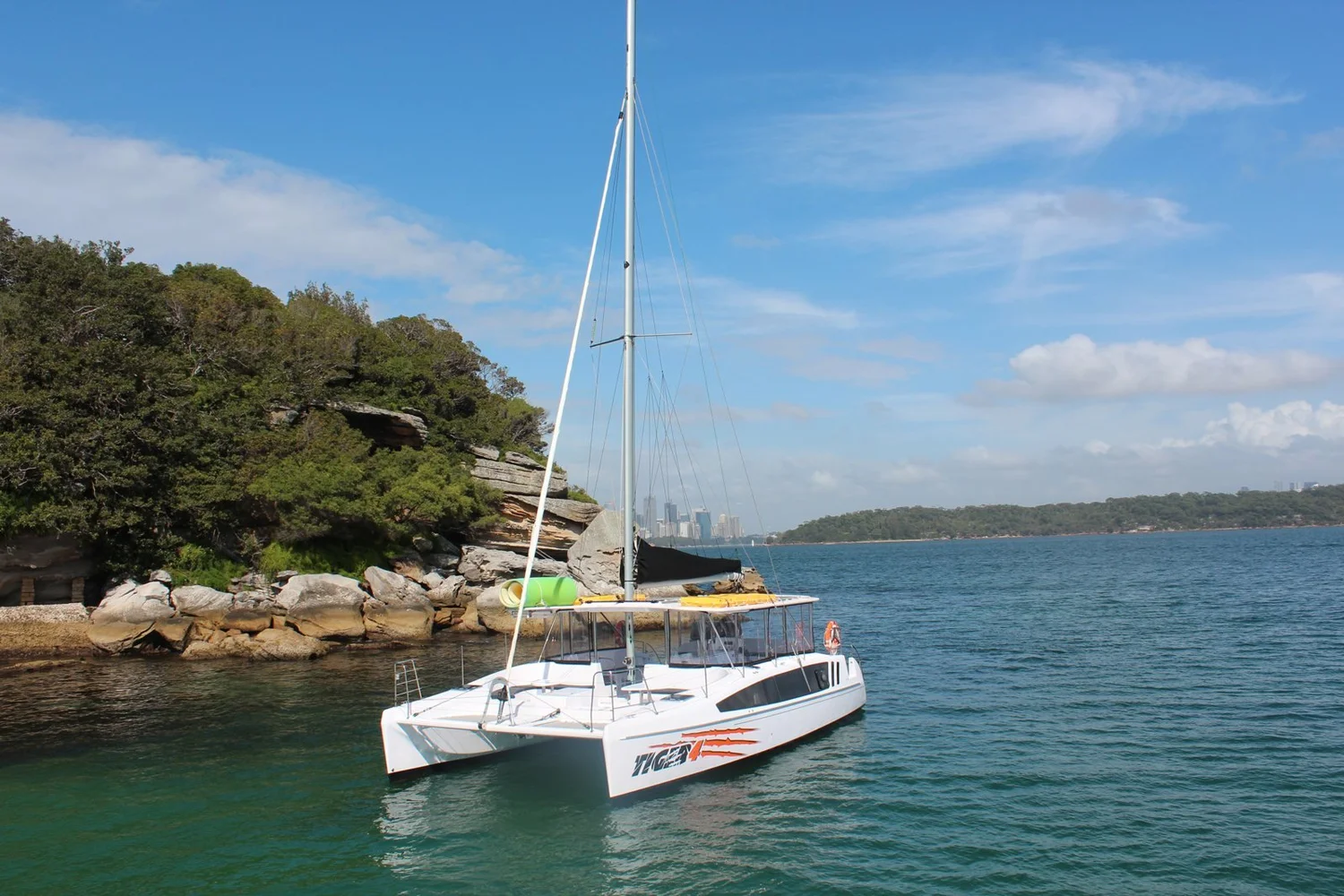 Tiger 3, a white sailing catamaran, at anchor in a Sydney Harbour bay