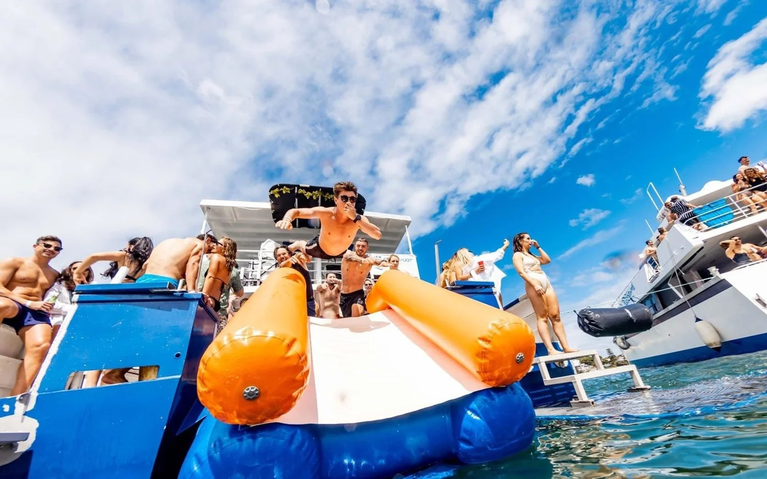 Guests on the inflatable slide off Barefoot Spirit on Sydney Harbour