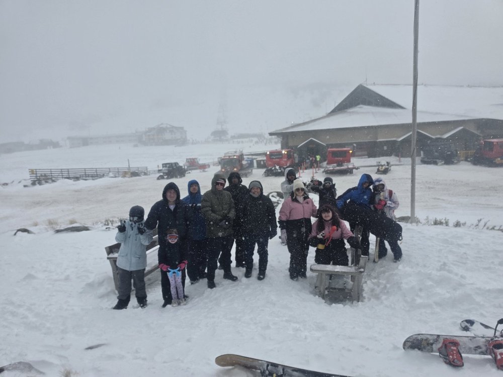 Crew smiling through fresh snowfall at the resort on a snow tour