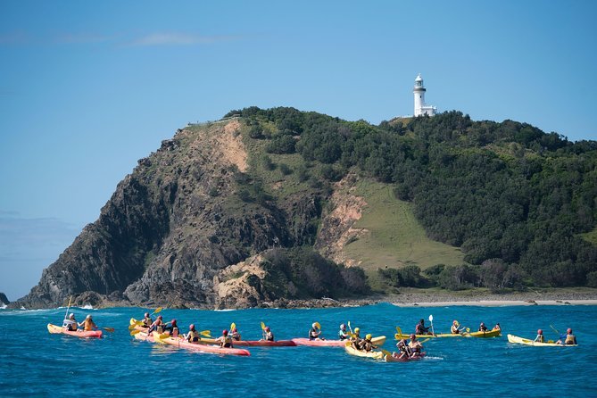 Kayakers paddling below the Cape Byron lighthouse headland at Byron Bay