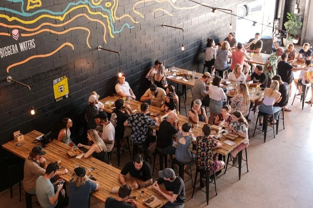 Groups seated at long tables in a Queensland brewery taproom