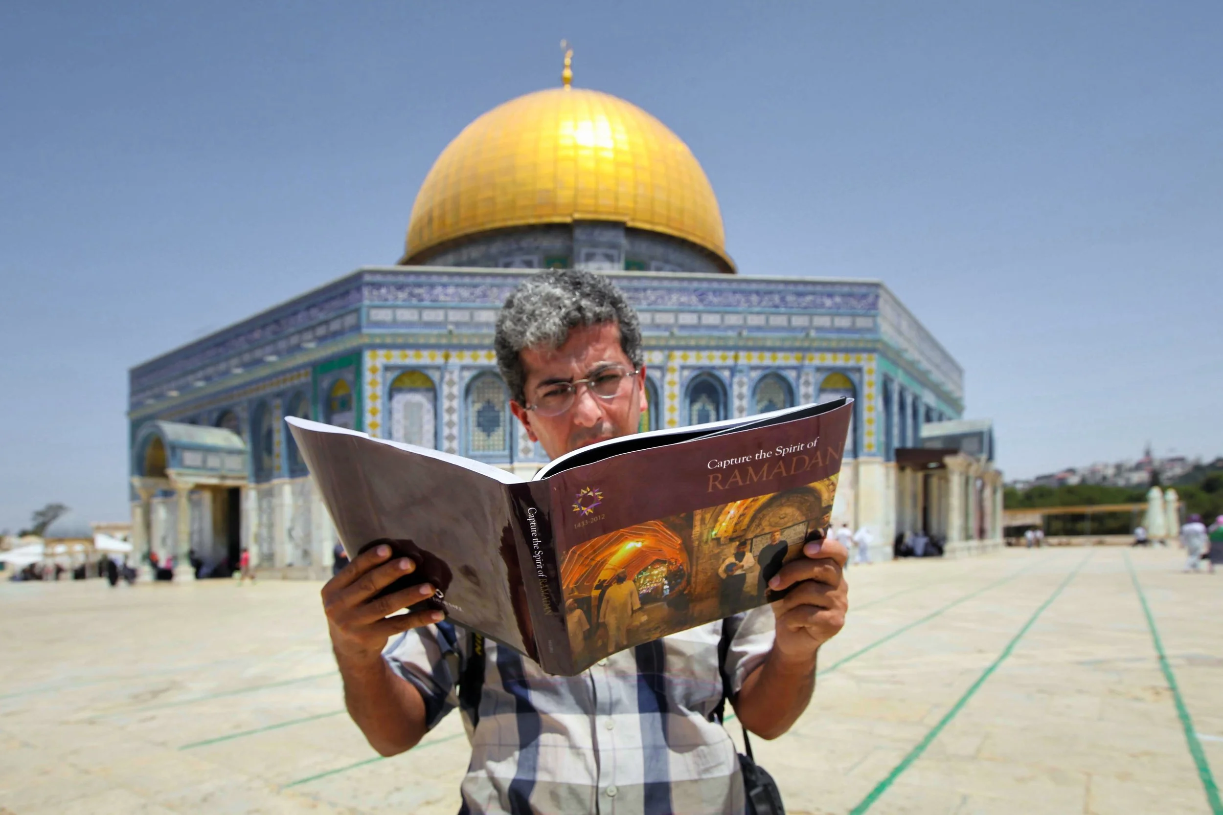 Competition winner Mahmoud Ilean holding the Capture the Spirit of Ramadan book at the Dome of the Rock, Jerusalem