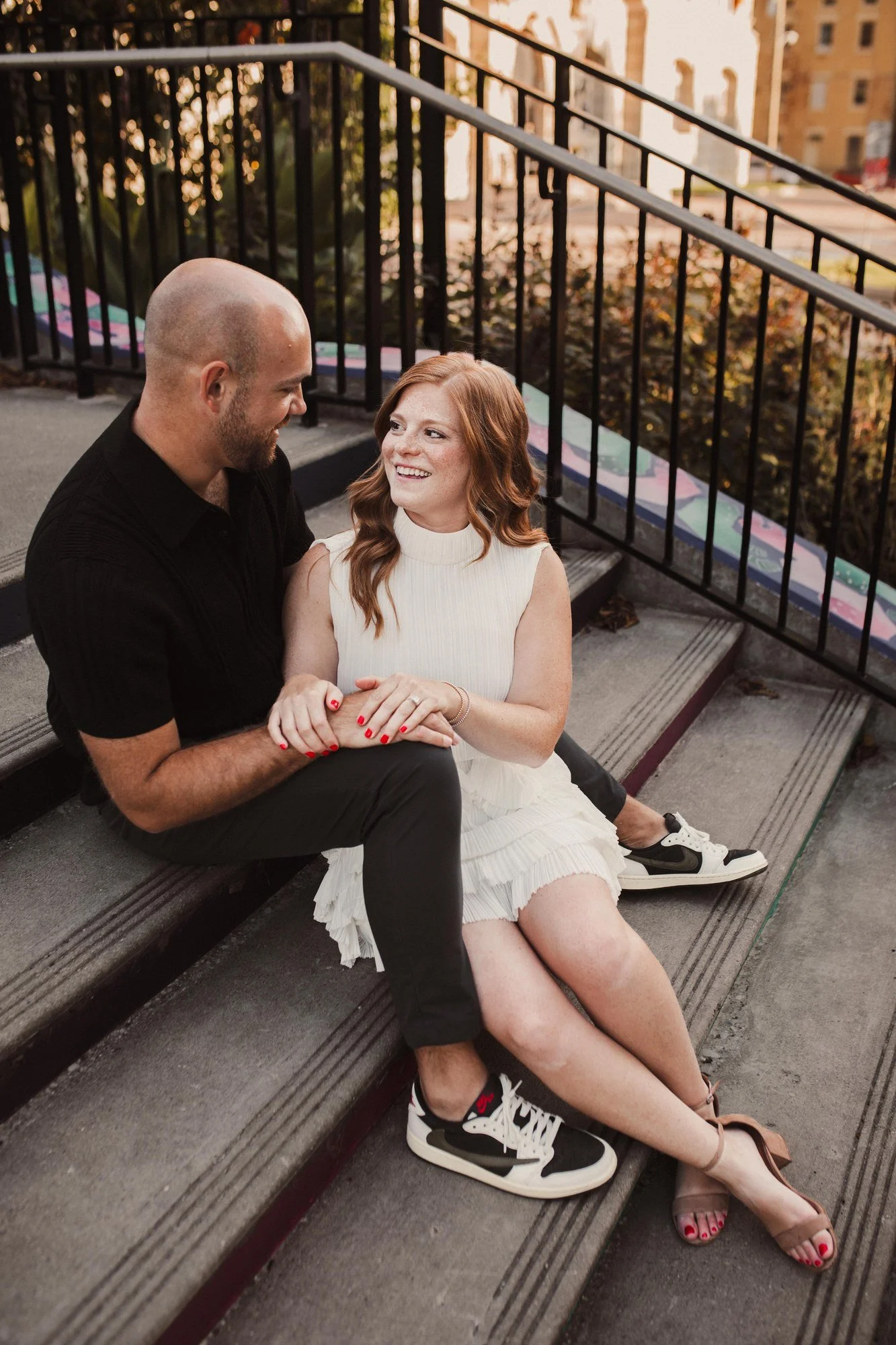Jacob and Erin seated together on stone steps beside black iron railings.