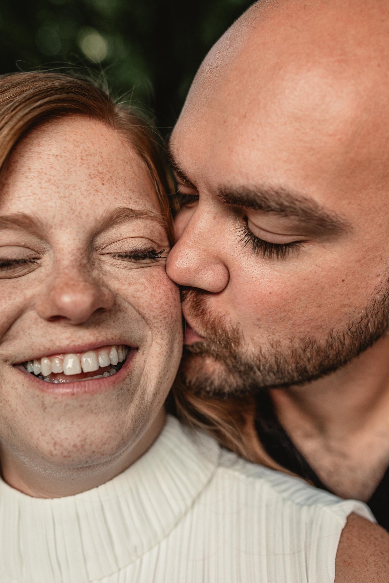 Jacob kissing Erin’s cheek as she smiles with her eyes closed.