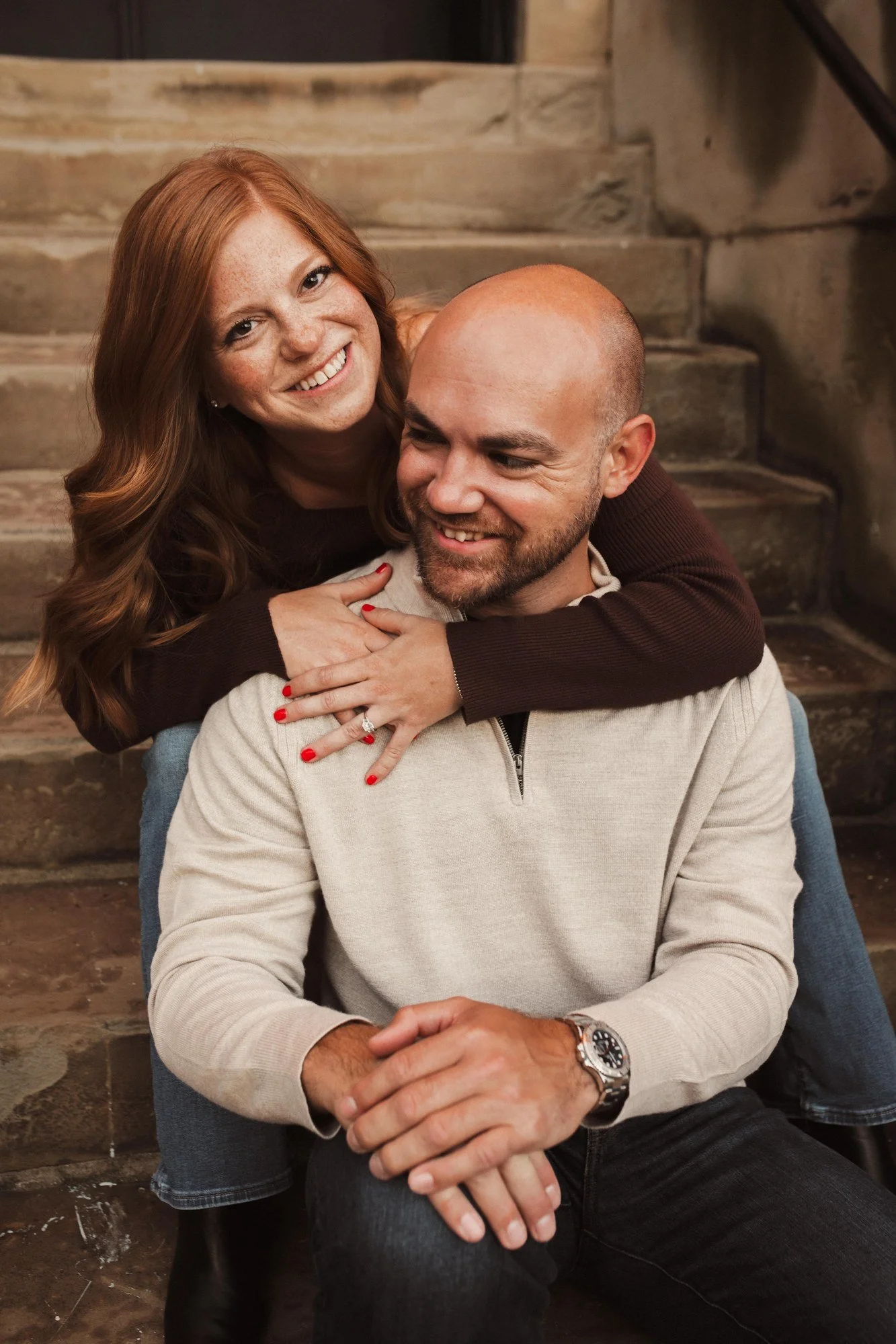 Jacob and Erin smiling together while seated on outdoor stone steps.