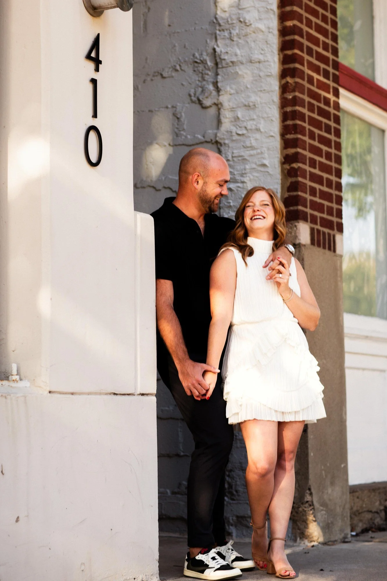 Jacob and Erin holding hands and looking at each other beside a stone doorway.