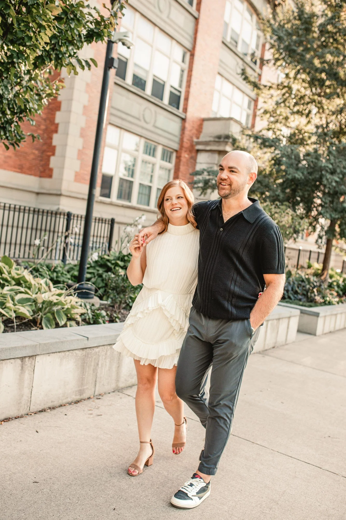 Jacob and Erin walking hand in hand along a tree-lined Cincinnati sidewalk.