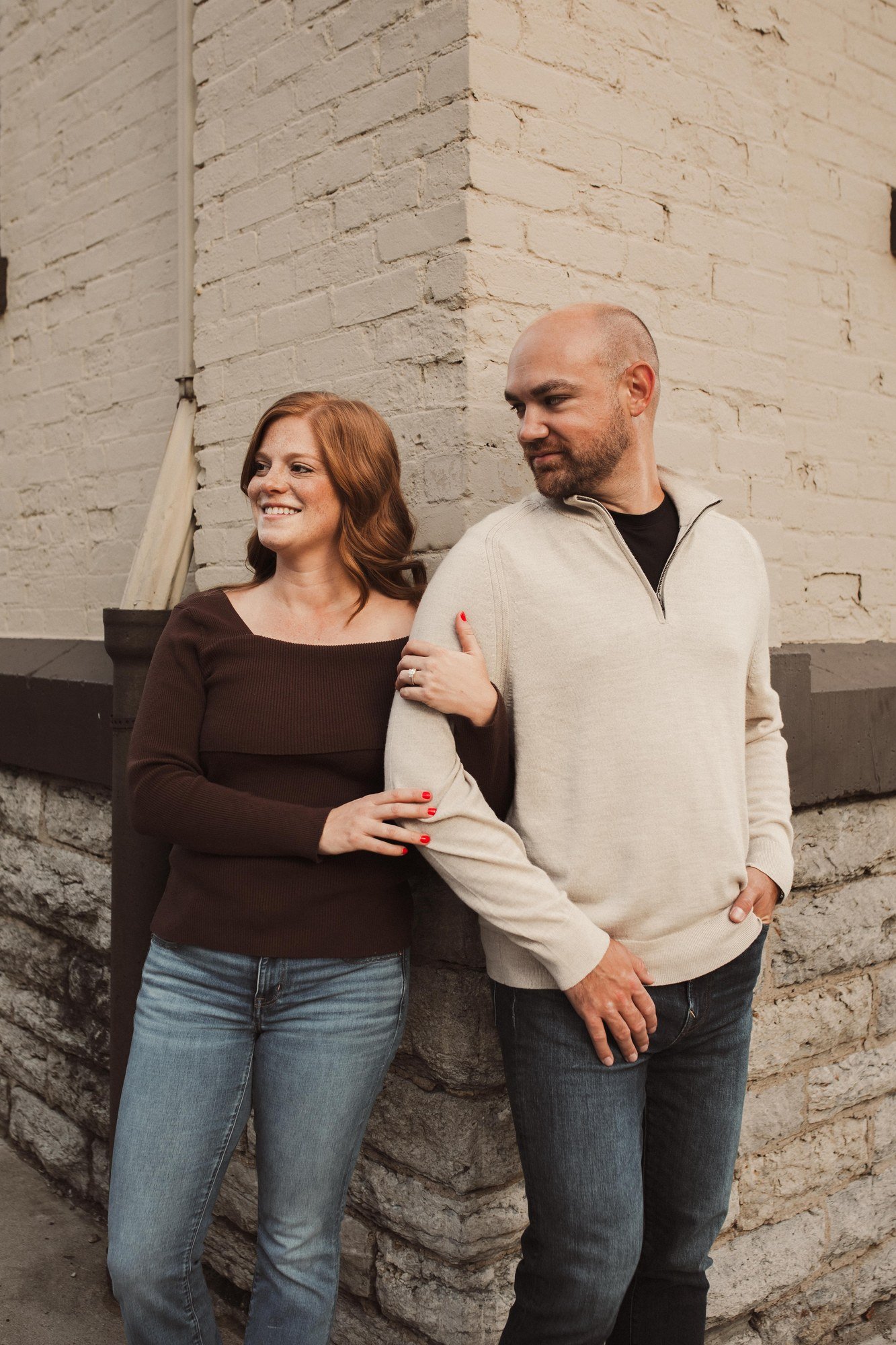 Jacob and Erin smiling together against a pale stone wall.