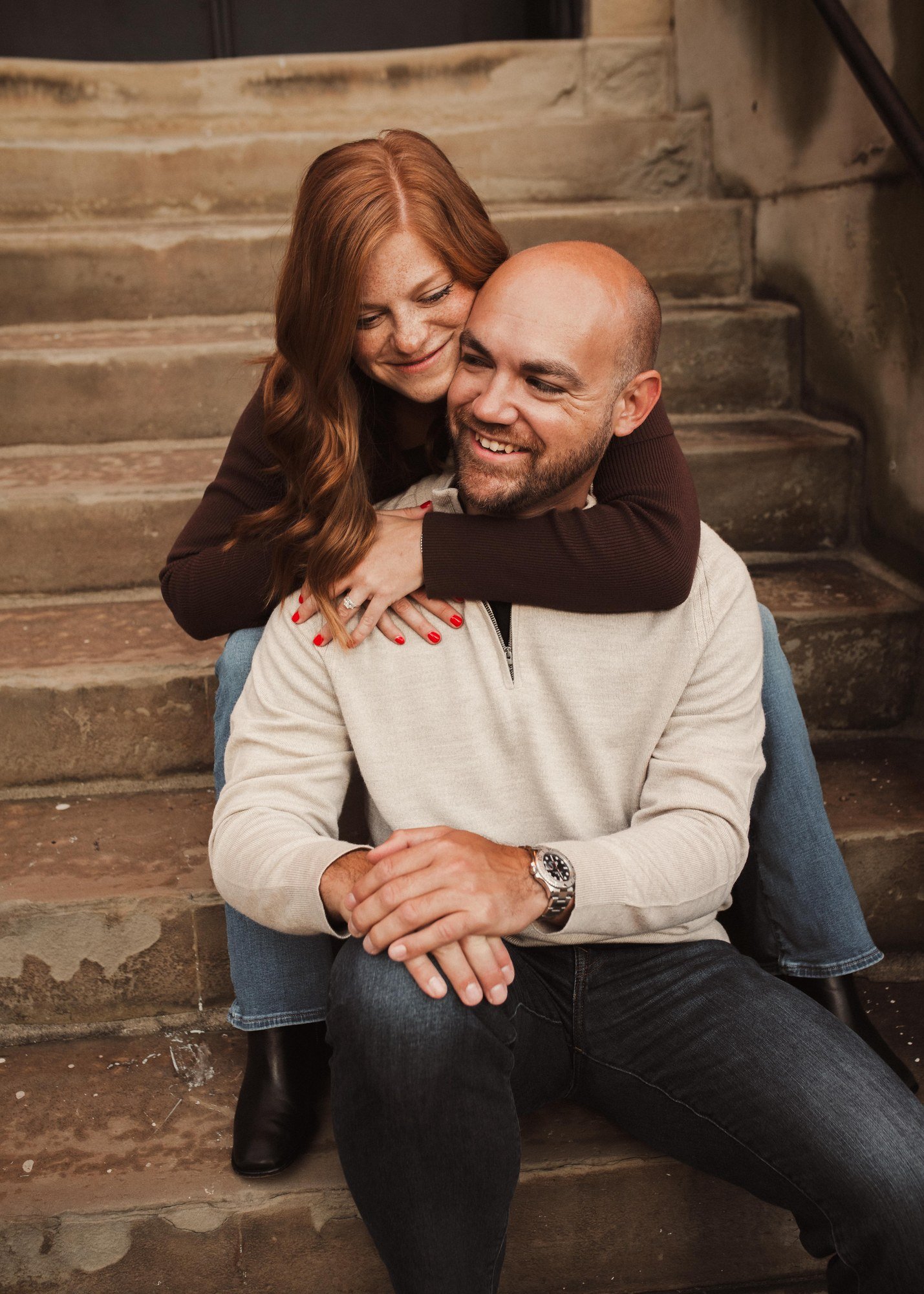 Erin laughing as she embraces Jacob from behind on the steps.