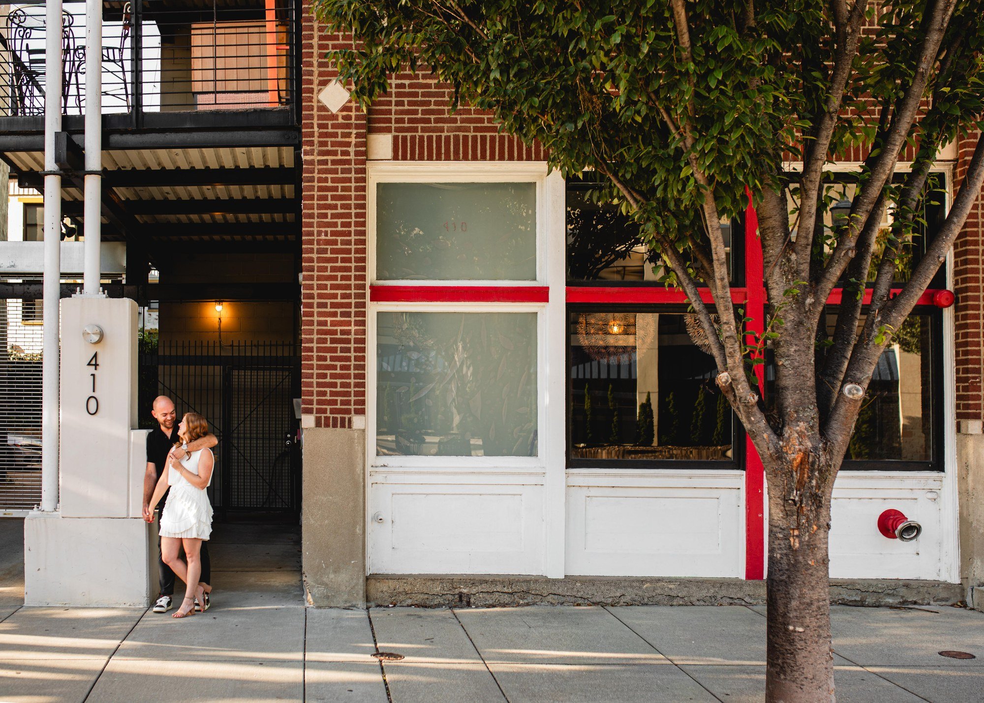 Jacob and Erin embracing beside a brick storefront in Over-the-Rhine, Cincinnati.