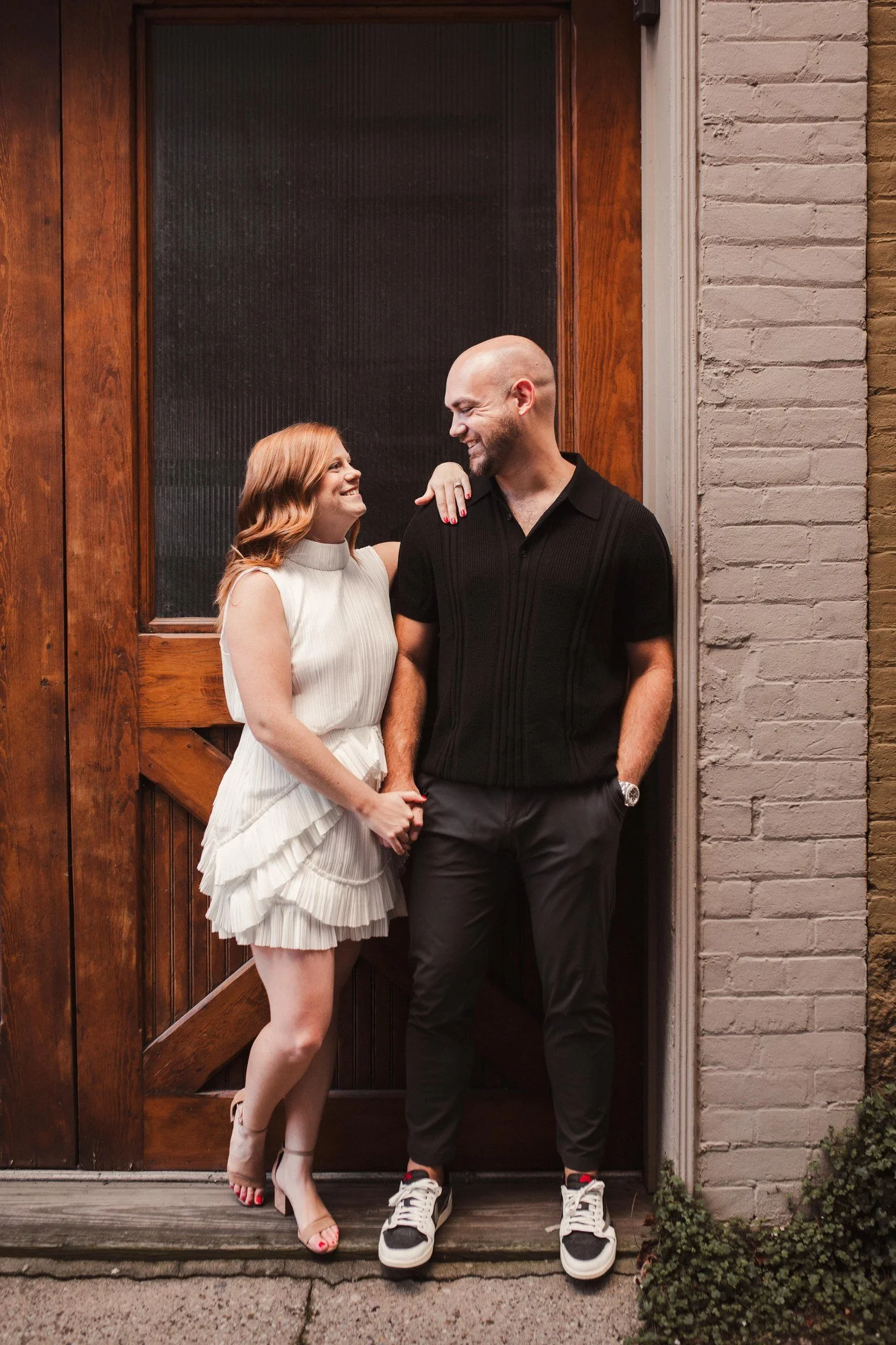Jacob and Erin standing close in front of tall wooden doors.