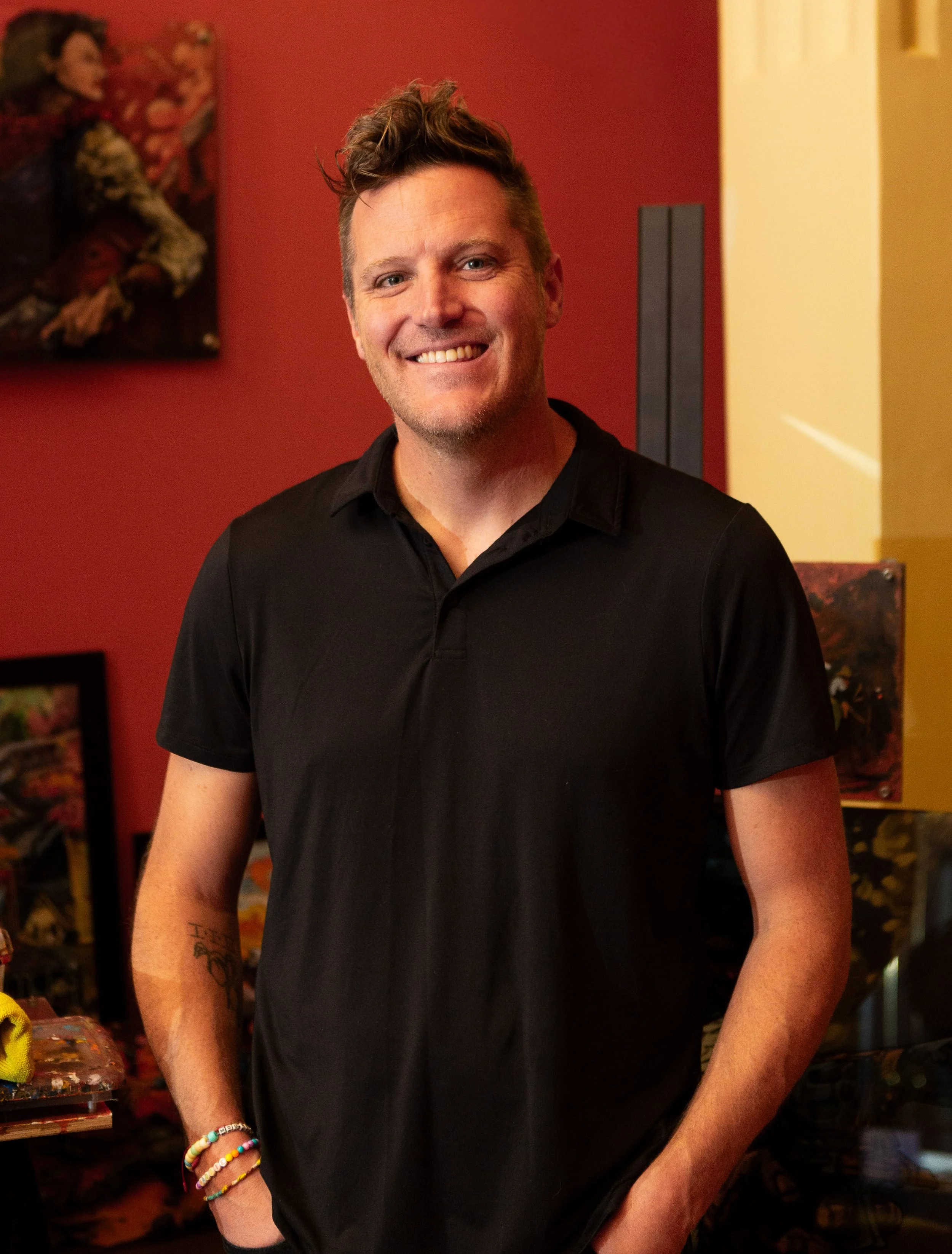 Colorado western artist Cody Kuehl at the Go West Film Festival in Greeley, with his artwork displayed behind him