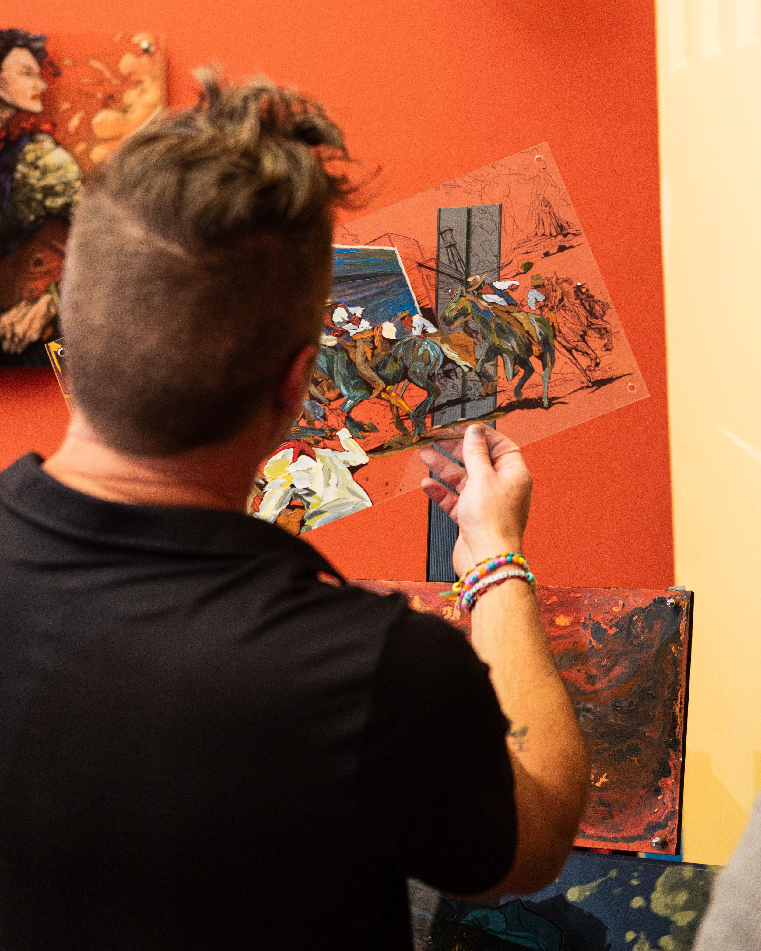 Cody Kuehl holding up a transparent layer of one of his artworks at the Go West Film Festival, showing how his paintings are built