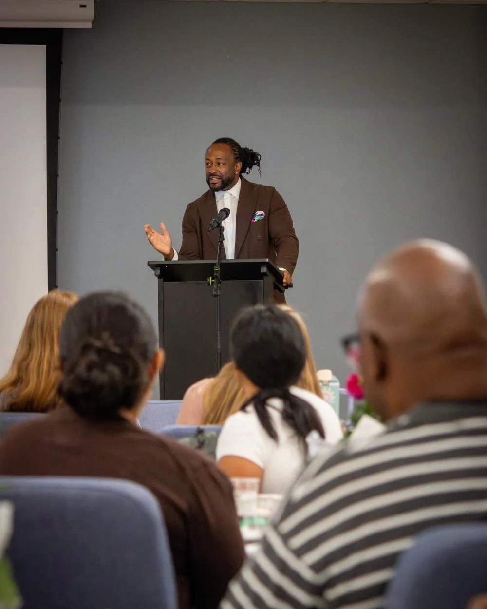 Keynote speaker and executive coach Attah Obande speaking from a podium to an engaged audience
