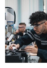 Photograph to two vocational technical college students working with robotic tool