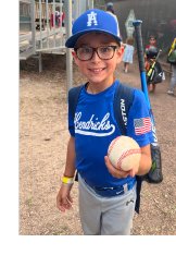 Photograph of boy holding out baseball