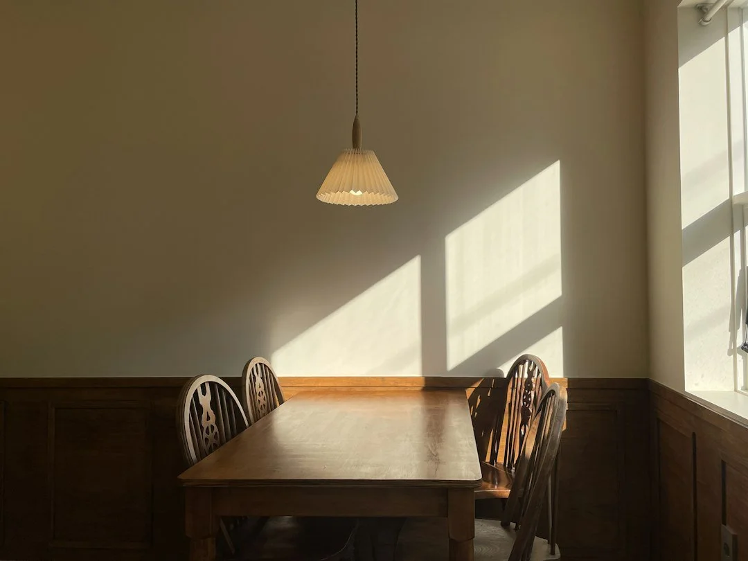 An empty kitchen table under a pendant light in the late afternoon