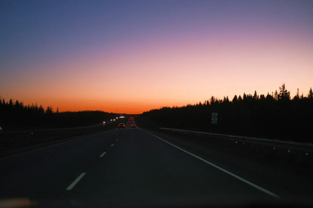 An open road at dusk with the sky turning orange